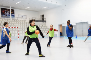 Image illustrant, des collégiens jouant au handball dans un gymnase