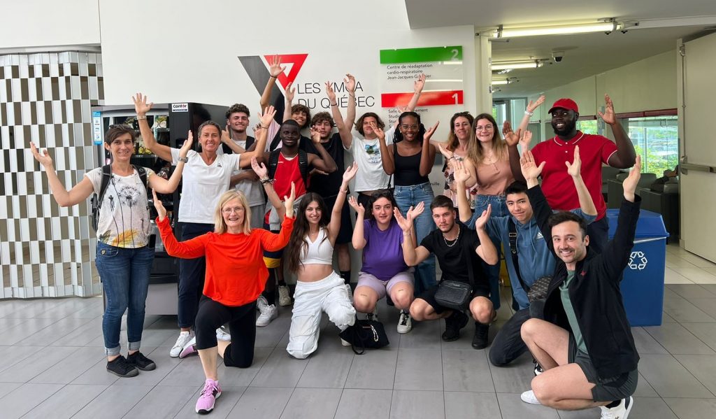 Photo collégiale de dix-huit personnes levant les bras en forme de "y"