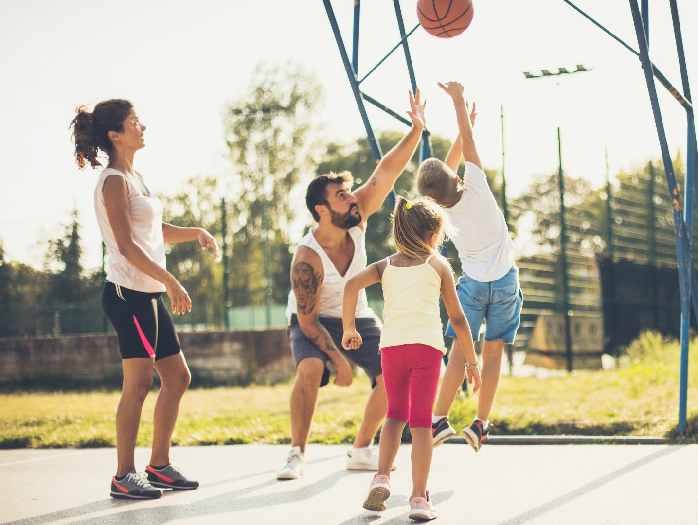 Une famille qui joue au basket avec un papa, une maman et deux enfants