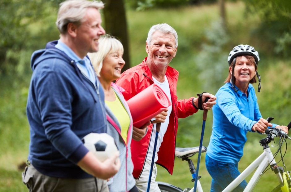 Quatre personne agées qui se promènent, l'une a un ballon, l'autre un tapis de sport, le troisième des batons de marche et la dernière un vélo