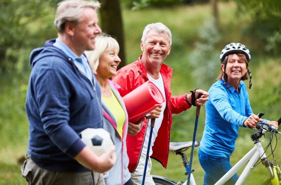 Quatre personne agées qui se promènent, l'une a un ballon, l'autre un tapis de sport, le troisième des batons de marche et la dernière un vélo