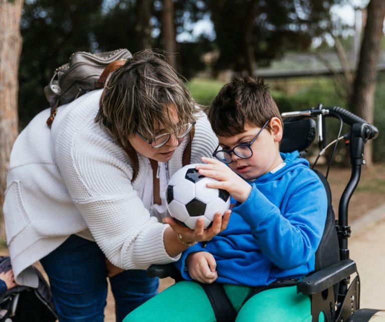 Une maman rapportant le ballon de football à son enfant en fauteuil roulant