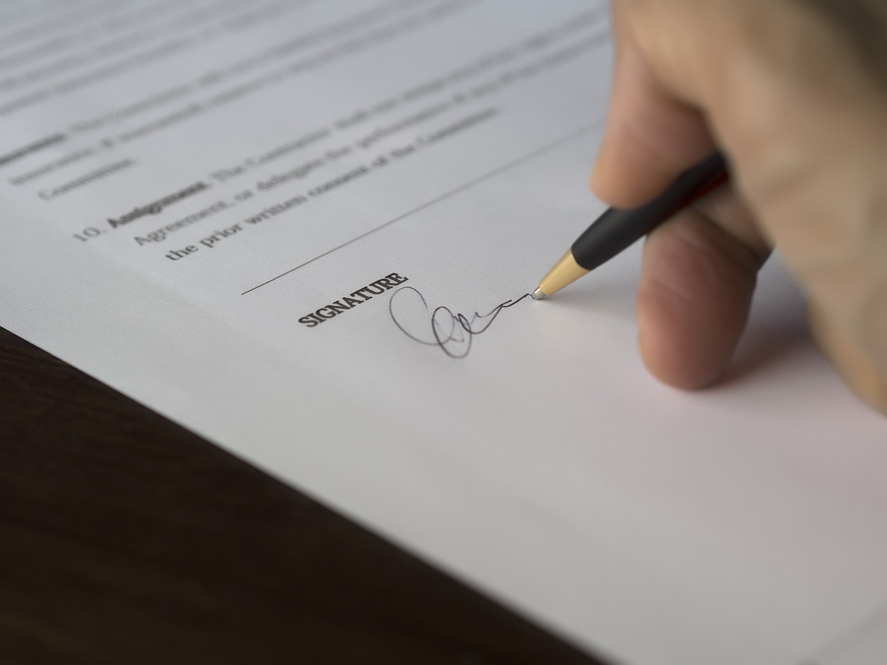 Une main tenant un stylo entrain de signer un document