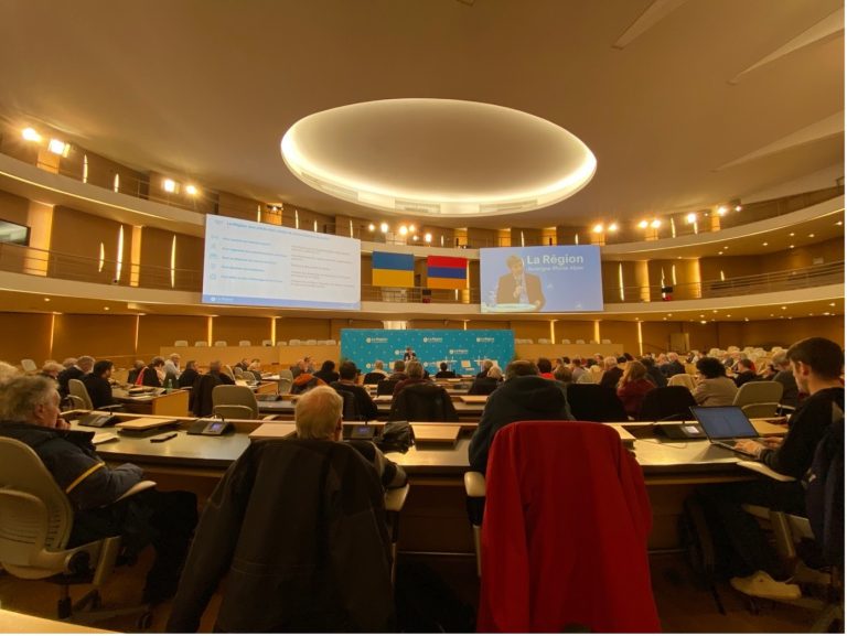 L'image représente la réunion des Ligues et Comités sportifs régionaux de la Région Auvergne-Rhône-Alpes. On peut y voir une projection d'un PowerPoint et d'Alexandre Nanchi (conseiller régional aux sports) qui intervient pour l'occasion. Le tout se déroule dans un amphithéâtre avec l'ensemble des représentants des ligues te comités sportifs régionaux.