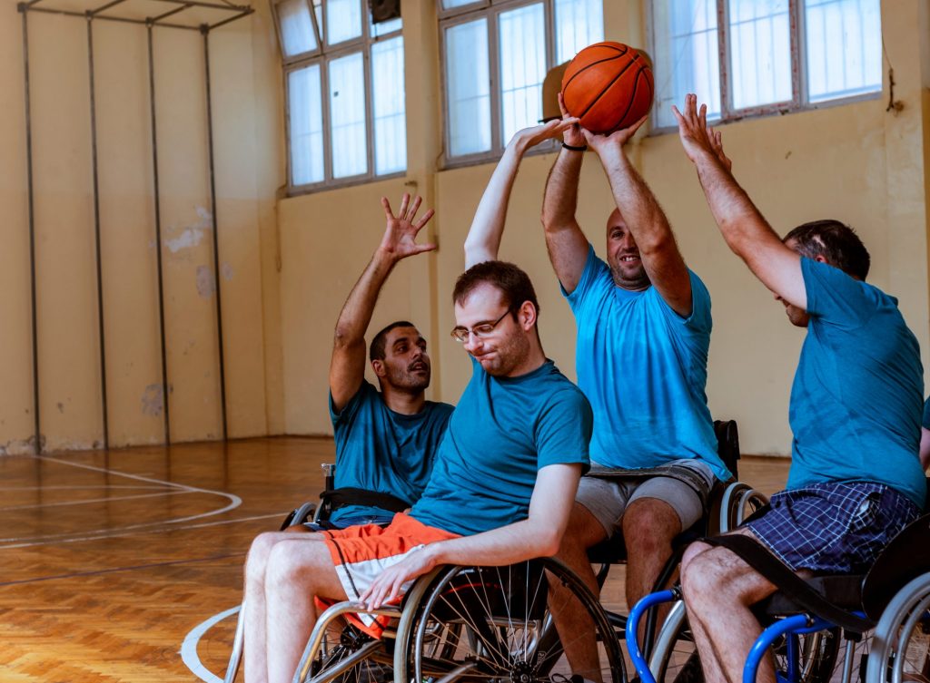 4 hommes en fauteuil roulant jouant au basketball