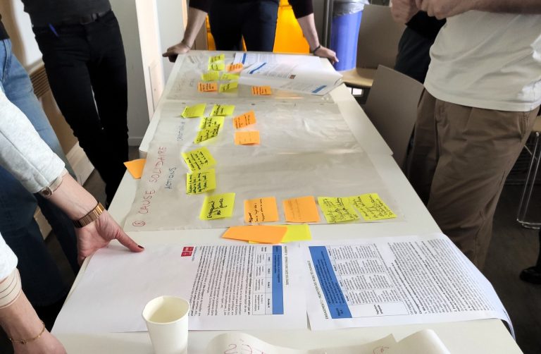 Participants qui sont autour d'une table et qui mettent des post-it pour présenter leurs idées pour le plan d'actions