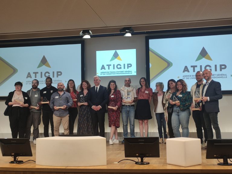 Groupe de personnes alignées sur scène et tenant dans la main un prix