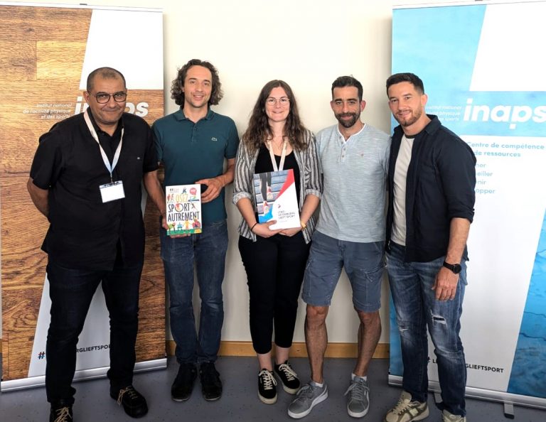 Groupe de personnes posant, dont 2 personnes tenant chacun un livre dans leurs mains.