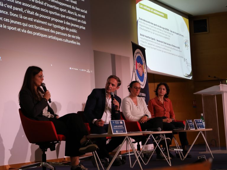4 personnes sur une estrade. L'une d'elles parle au micro.