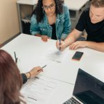 A couple discusses adoption papers with a professional in an office environment.