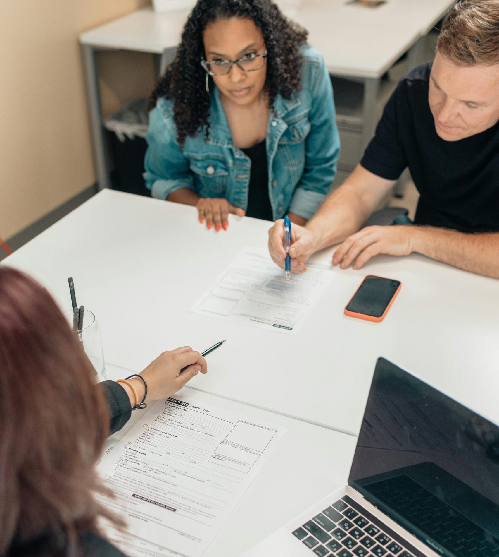 A couple discusses adoption papers with a professional in an office environment.