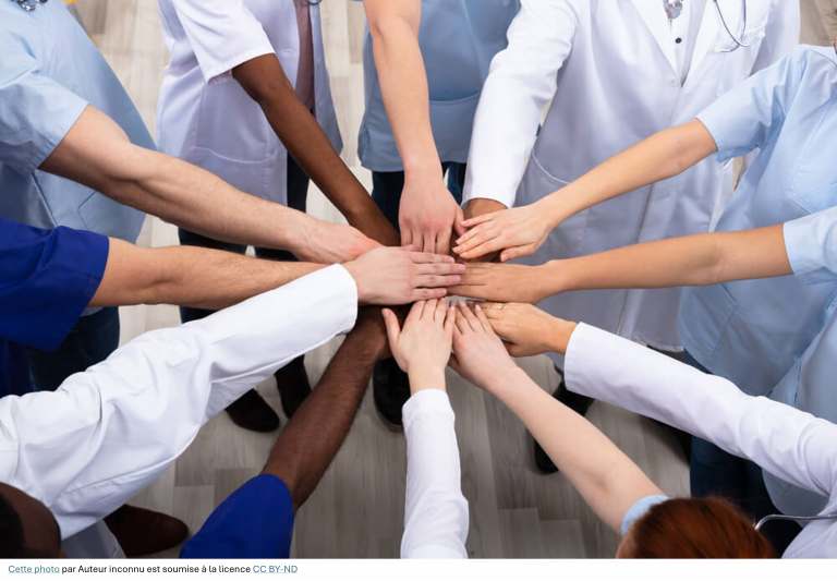 Soignants en blouse qui se mettent leur main au dessus des unes des autres
