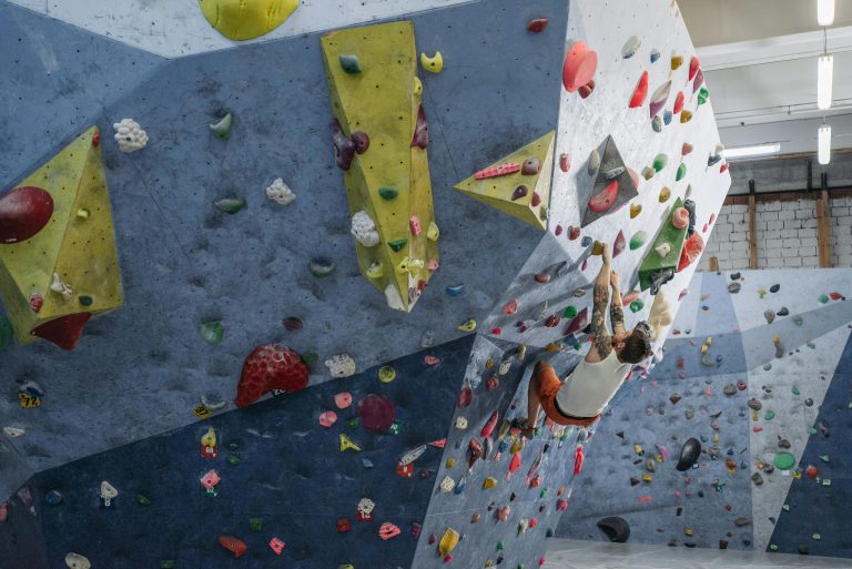 Focused athlete climbing an indoor bouldering wall, showcasing strength and agility.
