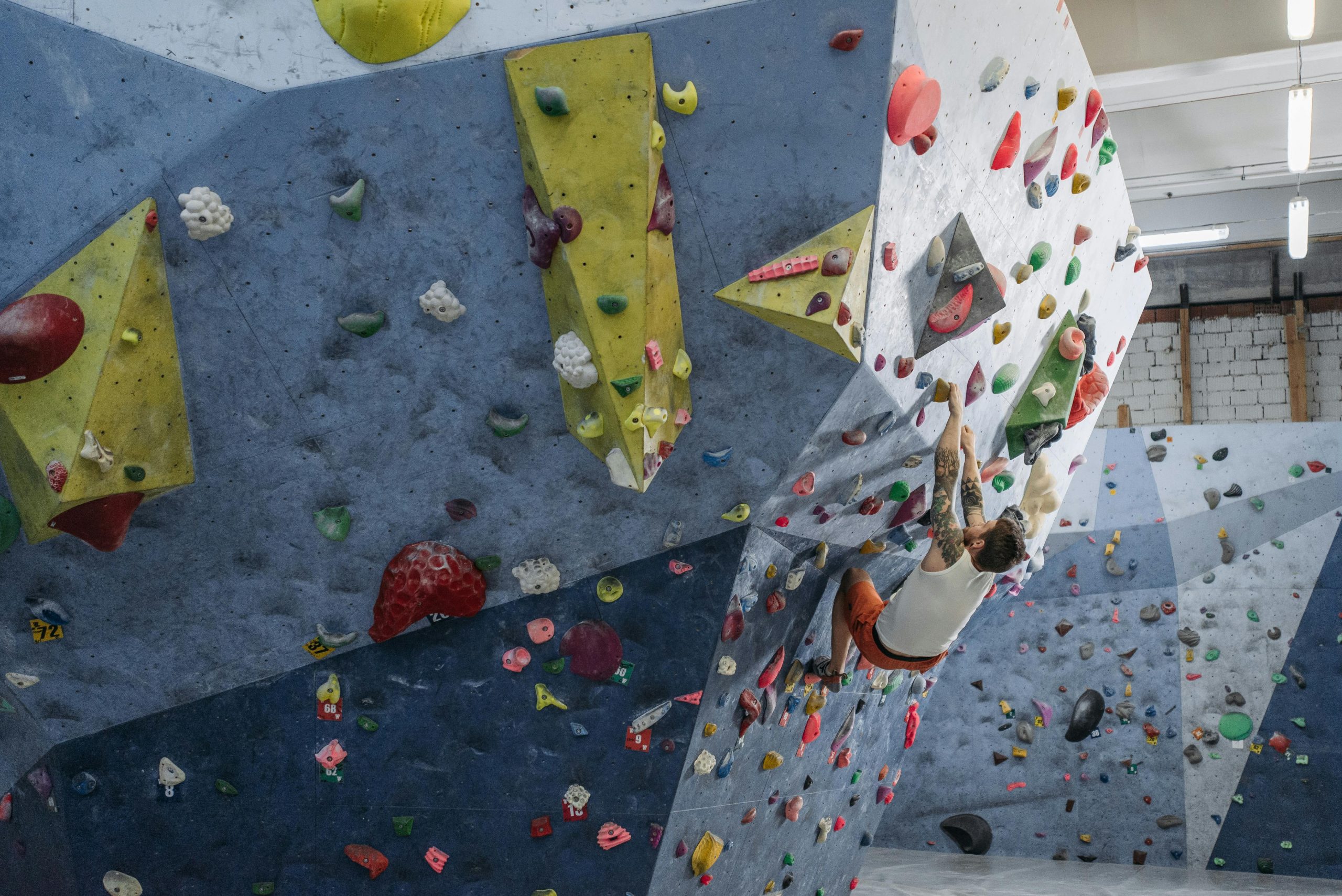 Focused athlete climbing an indoor bouldering wall, showcasing strength and agility.