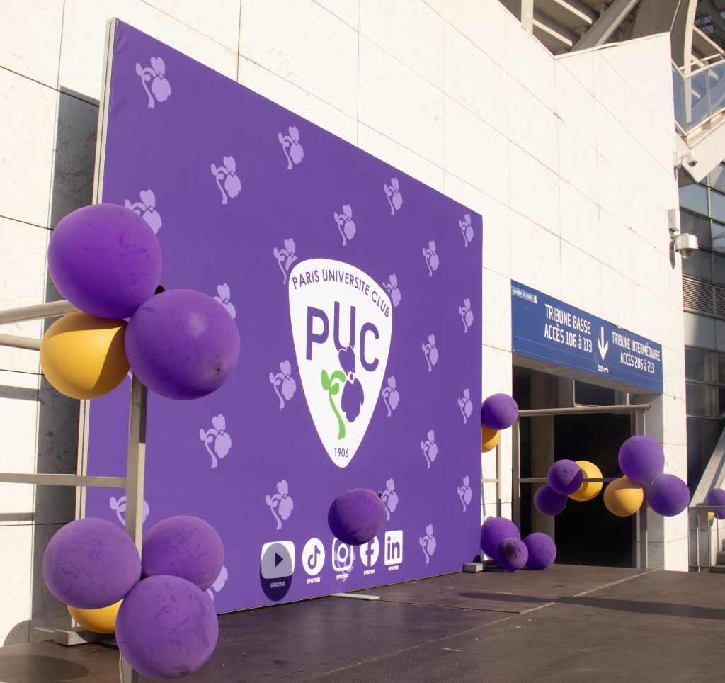 Scène avec dans le fond une grande affiche du logo du PUC et autours des ballons de baudruche